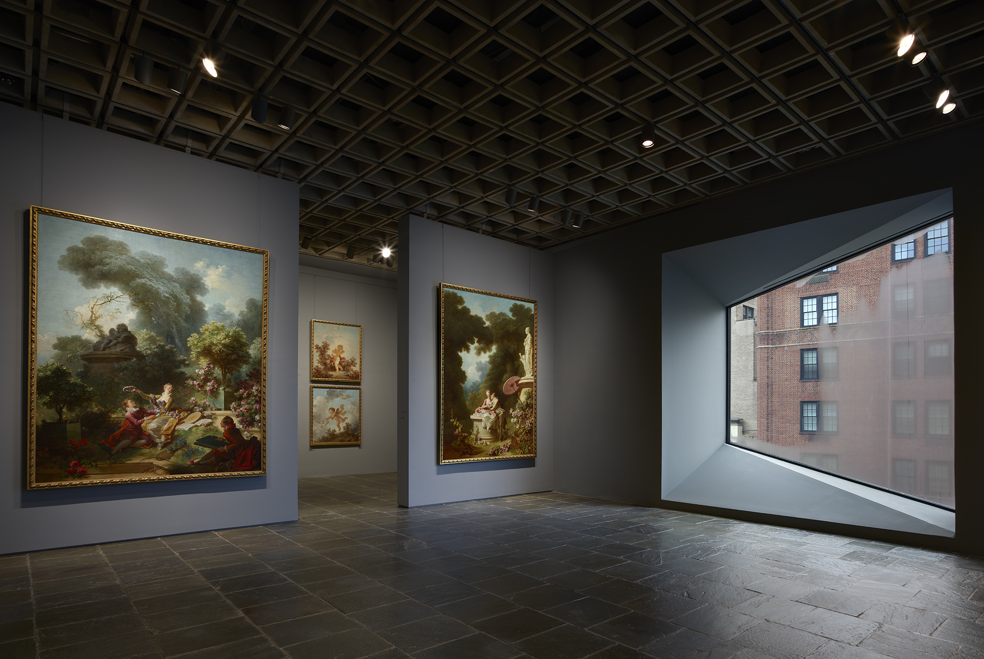 Four grand panels of Fragonard’s series The Progress of Love are shown together at Frick Madison in a gallery illuminated by one of Marcel Breuer’s trapezoidal windows. This view shows two of the 1771–72 paintings, with two later overdoors visible in the next gallery; photo: Joe Coscia